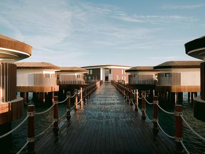 Reihe von Überwasser-Bungalows auf Holzsteg unter blauem Himmel bei Sonnenuntergang.