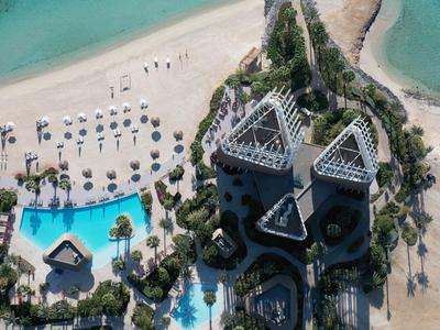 Luxushotel am weißen Sandstrand mit blauen Pools und türkisfarbenem Meer.