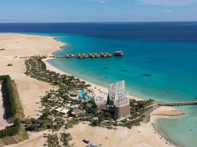 Luxushotel an sandigem Strand mit türkisfarbenem Meer und klarem Himmel.