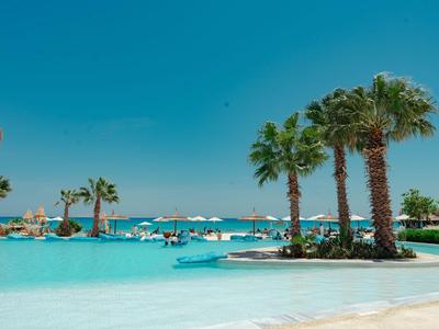 Strandhotel mit Palmen und klarem blauem Wasser unter wolkenlosem Himmel.