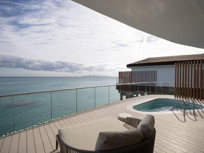 Moderner Balkon mit Infinity-Pool und Meerblick unter bewölktem Himmel.