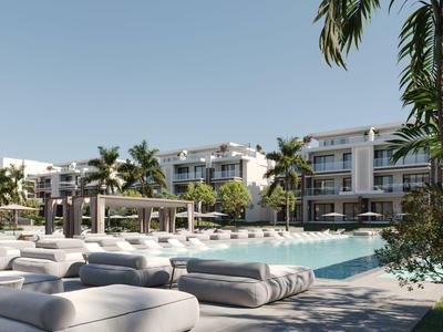 Modernes Hotel mit Pool, Sonnenliegen und Palmen unter klarem Himmel.
