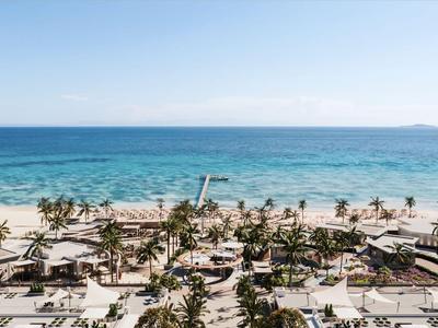 Weißer Sandstrand mit Palmen und blauer See unter klarem Himmel in einem Ferienresort.
