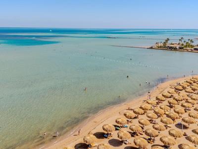 Strand mit Sonnenschirmen und ruhigem, blauem Meer, ideal für einen entspannten Urlaub.