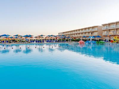 Großer Swimmingpool vor einem mehrstöckigen Hotel mit Liegestühlen und Sonnenschirmen.