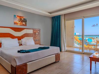 Hell eingerichtetes Hotelzimmer mit Doppelbett und Balkon mit Meerblick.
