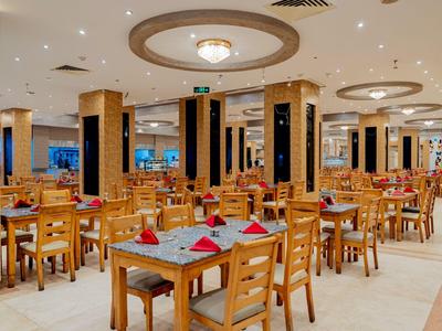 Großer Hotelrestaurant-Saal mit Holztischen und -stühlen, festlich gedeckt mit roten Servietten.