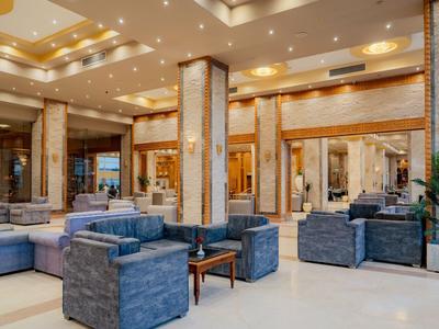 Geräumige Hotellobby mit modernem Design, blauen Sesseln und warm beleuchteten Deckenakzenten.