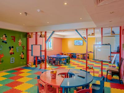 Bunter Kinderspielraum mit Tischen, Stühlen und Knetmaterialien, lebendige Wandgestaltung.