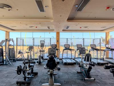 Ein moderner Fitnessraum mit Laufbändern und Fitnessgeräten mit Blick auf die Stadt.
