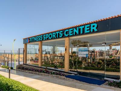 Modernes Fitness-Sportzentrum mit großen Fenstern und Blick auf eine grüne Umgebung.
