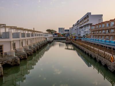 Ein ruhiger Kanal zwischen modernen Hotelgebäuden mit reflektierendem Wasser unter einem klare Himmel.