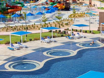Großer Außenpool mit Sonnenschirmen, Liegestühlen und Wasserrutschen in einem Hotelresort
