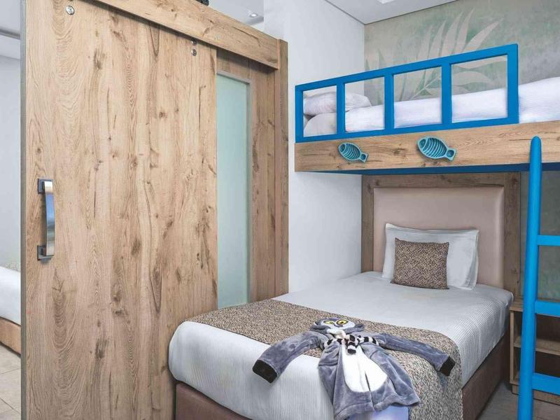 Camera con letto singolo e letto a castello in legno con accenti blu, arredo pulito e moderno.