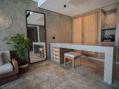 Moderner Raum mit Betonoptik, großem Spiegel, Sofa, Pflanze und langem Arbeitstisch aus Holz.
