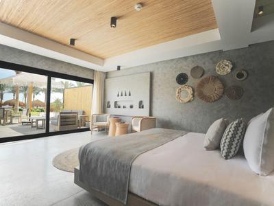 Modernes Schlafzimmer mit großem Bett, grauem Wandschmuck und Zugang zur Terrasse durch Schiebetüren.