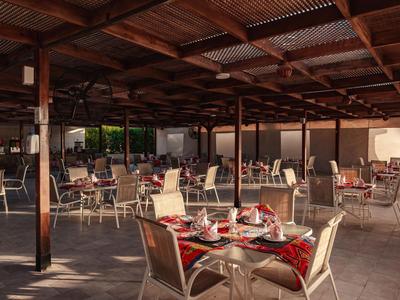 Open eetruimte met gedekte tafels, houten plafond en stoelen, ideaal voor hotelgasten.
