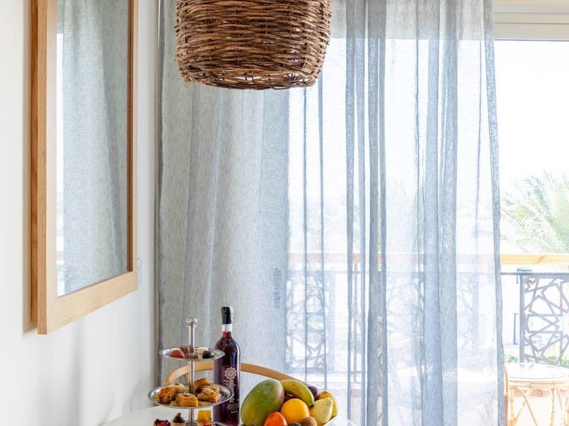 Przytulny stół śniadaniowy z owocami, winem i ciastkami obok okna z zasłonami.