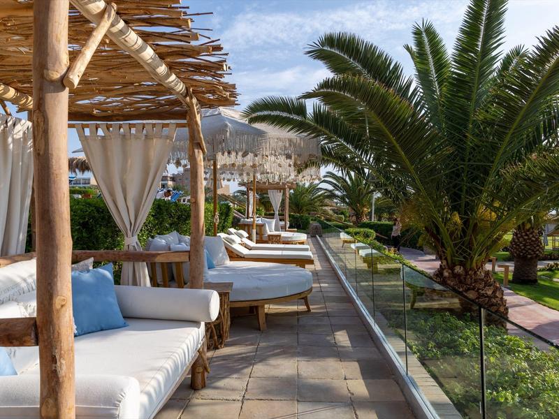 Relaksująca strefa wypoczynkowa z białymi sofami i palmami, idealna na wakacje w hotelu.