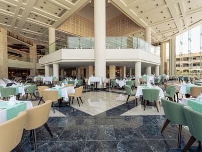 Spacious hotel lobby area with tables and chairs in neutral tones and natural light.