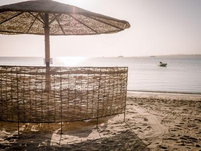 Sunshade and bamboo screen on the beach overlooking the sea and a boat