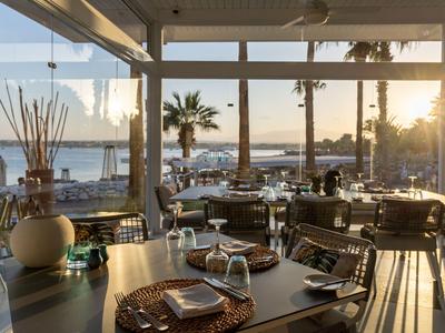 Brightly decorated restaurant interior with sea view at sunset.