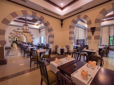 Elegantní restaurace s vysokými stropy a prostorným posezením v teplých barvách.