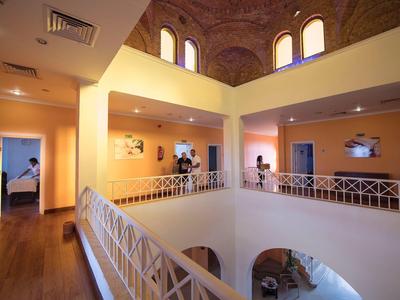 Wnętrze hotelu z otwartym atrium, balkonami i wysokimi sklepionymi sufitami.