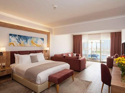 Modern hotelkamer met groot bed, zithoek en balkon met uitzicht op de stad.