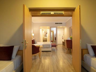 Uitzicht op een moderne hotelkamer met tweepersoonsbed, bureau en warme verlichting.