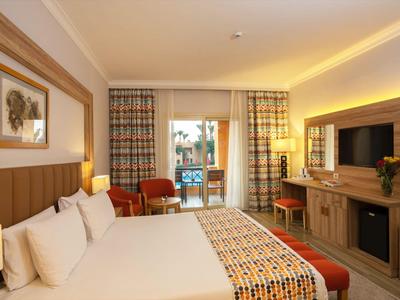 Moderne hotelkamer met groot bed, tv en toegang tot een balkon met uitzicht.