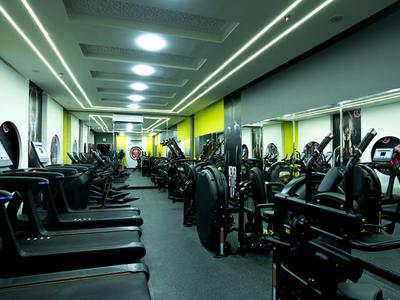 Moderne sportschool met tal van fitnessapparaten en heldere gele en grijze tinten.