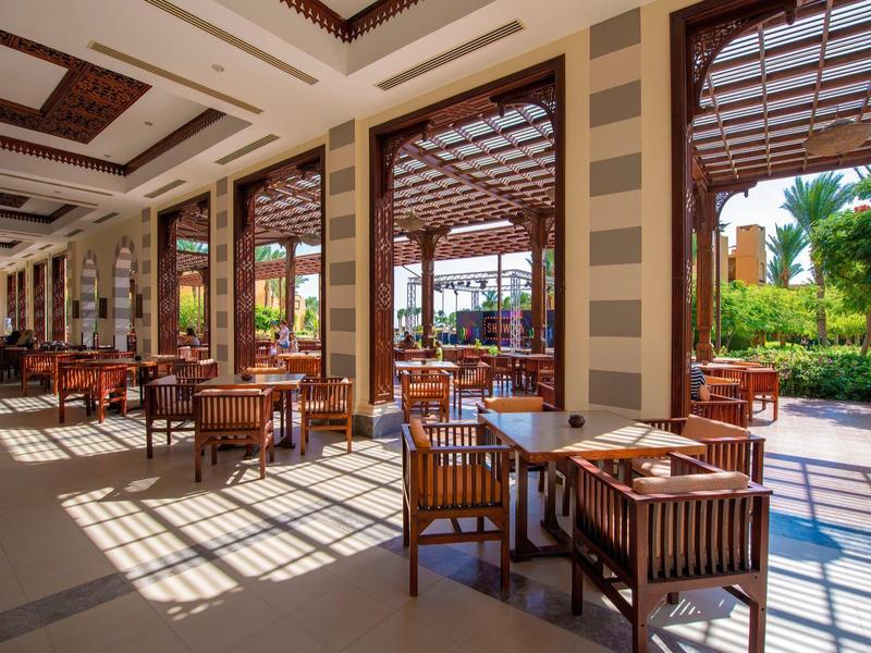 Jasna, otwarta restauracja z drewnianymi meblami i widokiem na zielony teren na zewnątrz.