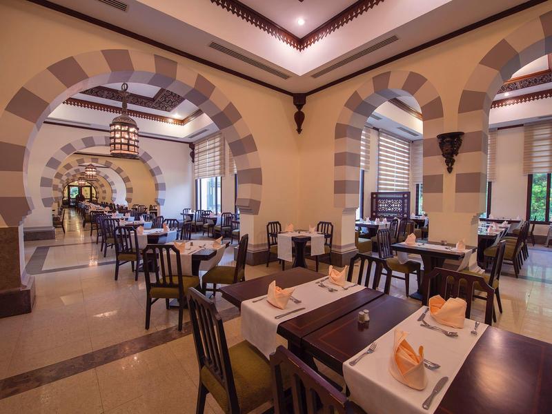 Elegancka restauracja z łukowymi ścianami, nakrytymi stołami i ciepłym oświetleniem.