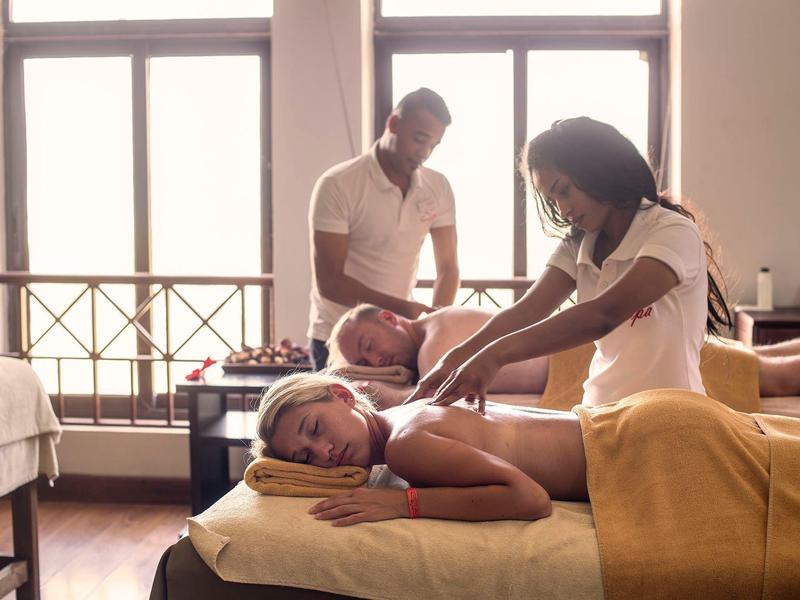 Dwie pary otrzymują relaksujące masaże w jasnym pokoju spa hotelu.