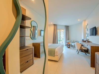 Moderner Hotelzimmerinnenraum mit Bett, Spiegel, Schreibtisch und Fenster mit Vorhängen.