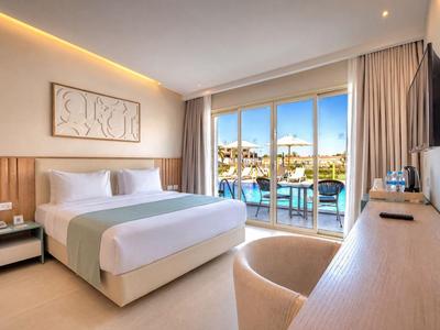 Modernes Hotelzimmer mit Doppelbett und Blick auf Außenpool durch große Glasfenster.