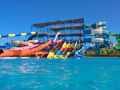 Mehrere bunte Wasserrutschen an einem großen Wasserspaß-Park unter klarem blauem Himmel.