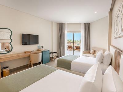 Modern hotel room with two double beds, desk, TV, and balcony with a view.