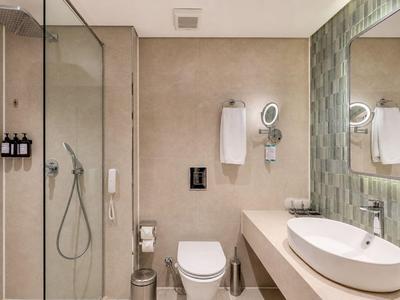 Modern bathroom with walk-in shower, toilet, and sink on a light-colored countertop.