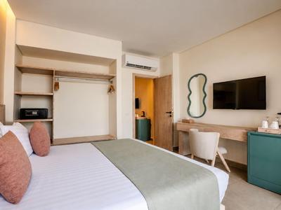 Modern hotel room with double bed, TV, air conditioning, and small desk.