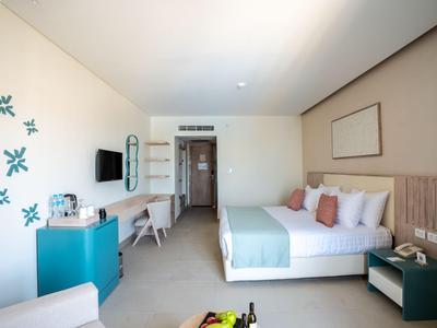 Habitación de hotel moderna con cama doble, TV, escritorio y decoración minimalista.