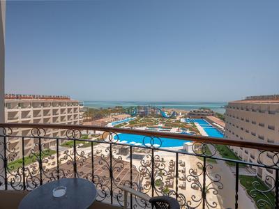 Balcón con mesa y sillas con vista a la piscina del hotel y al mar al fondo.