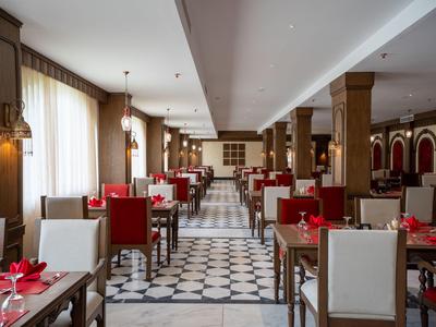 Comedor elegante con muebles de madera, acentos rojos y grandes ventanas en un hotel.