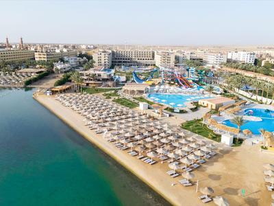 Gran complejo hotelero con piscinas, tumbonas y acceso directo al mar en un paisaje soleado.