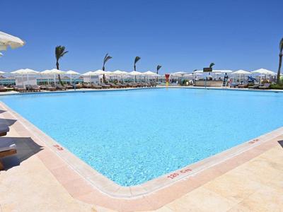 Großer Hotelpool mit blauer Wasserfläche, Sonnenschirmen und Liegestühlen im Freien.
