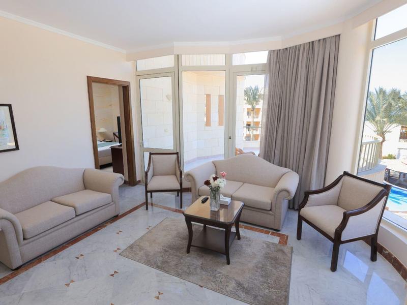 Bright hotel lounge with sofas, armchairs, coffee table, and large windows overlooking the pool.