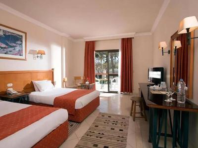 Hotelový pokoj se dvěma jednolůžky, psacím stolem, televizí a výhledem na terasu