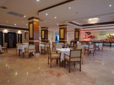 Prostorná hotelová jídelna s stolky, židlemi a moderním dekorací.