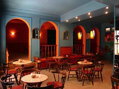 Salle à manger conviviale avec tables rondes, chaises et éclairage indirect chaleureux.